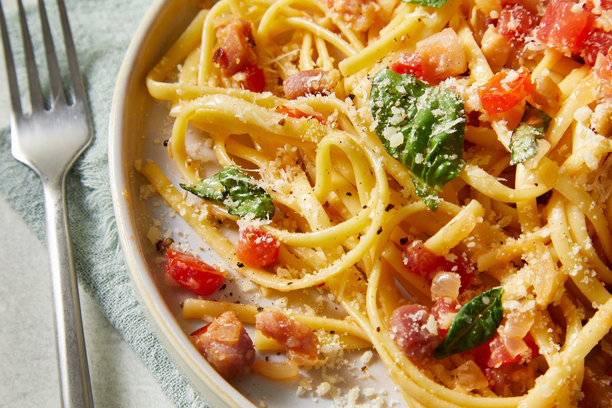 A plate of pasta with tomatoes and basil.