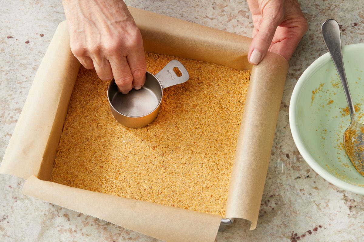 pressing crust into baking pan lined with parchment