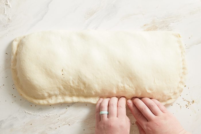 sealing the edges of the dough by pinching and folding